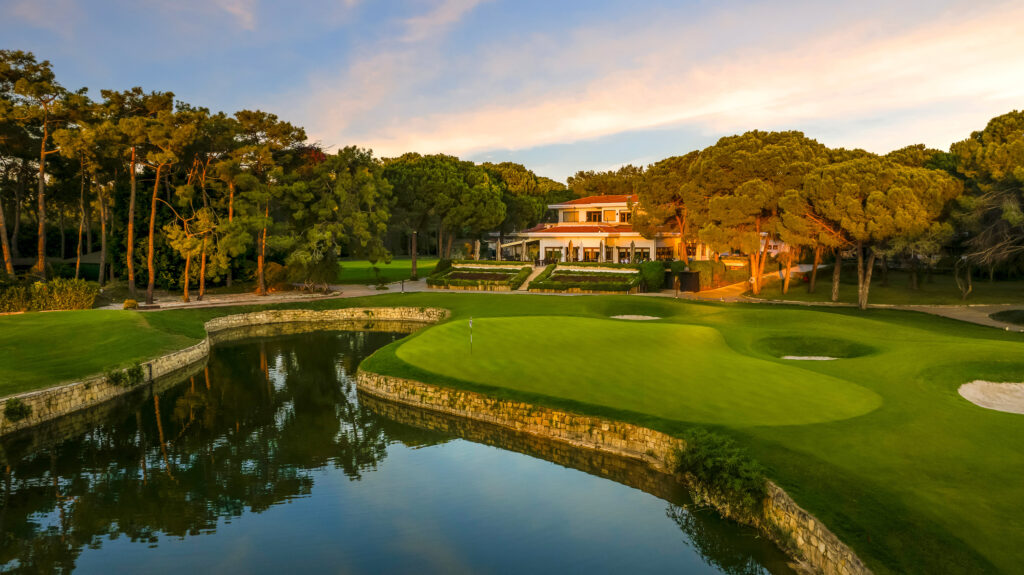 Hole with lake and trees around at The National Golf Course with building in background