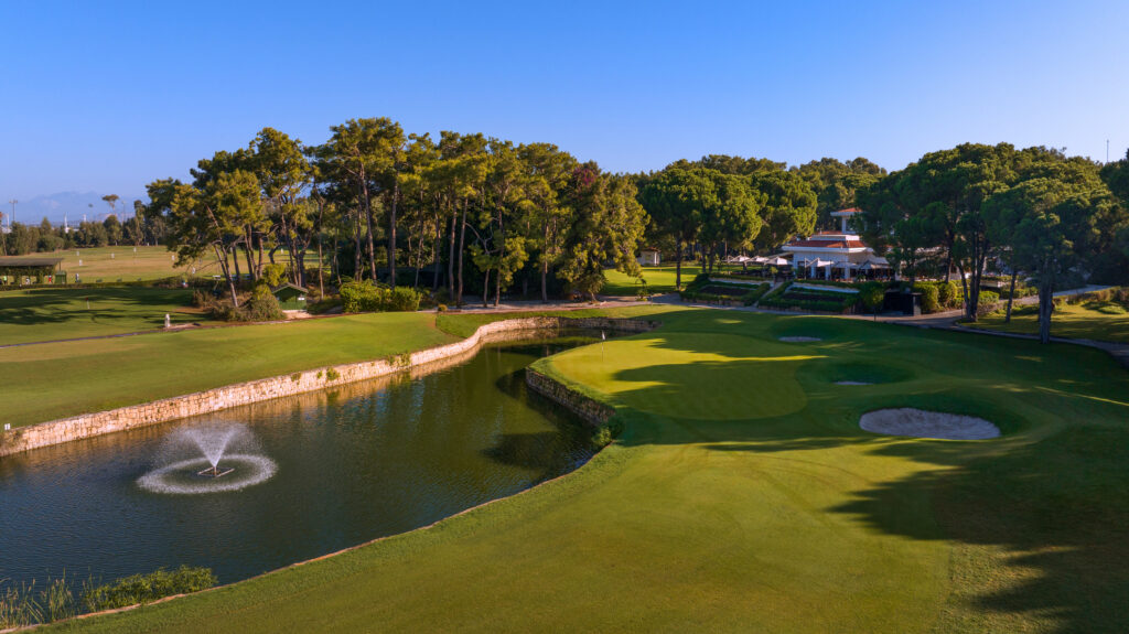 Hole with lake and trees around at The National Golf Course with building in background