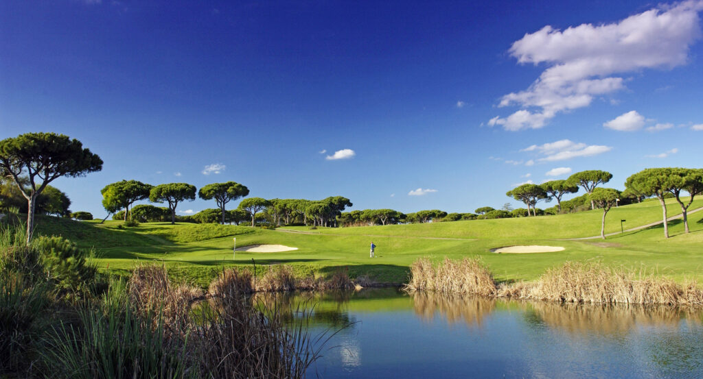 Person playing golf at Vale do Lobo Royal Golf Course with a lake in foreground