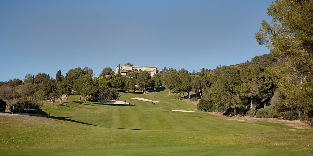 Fairway with trees around and building in distance at Vall D'Or Golf Course