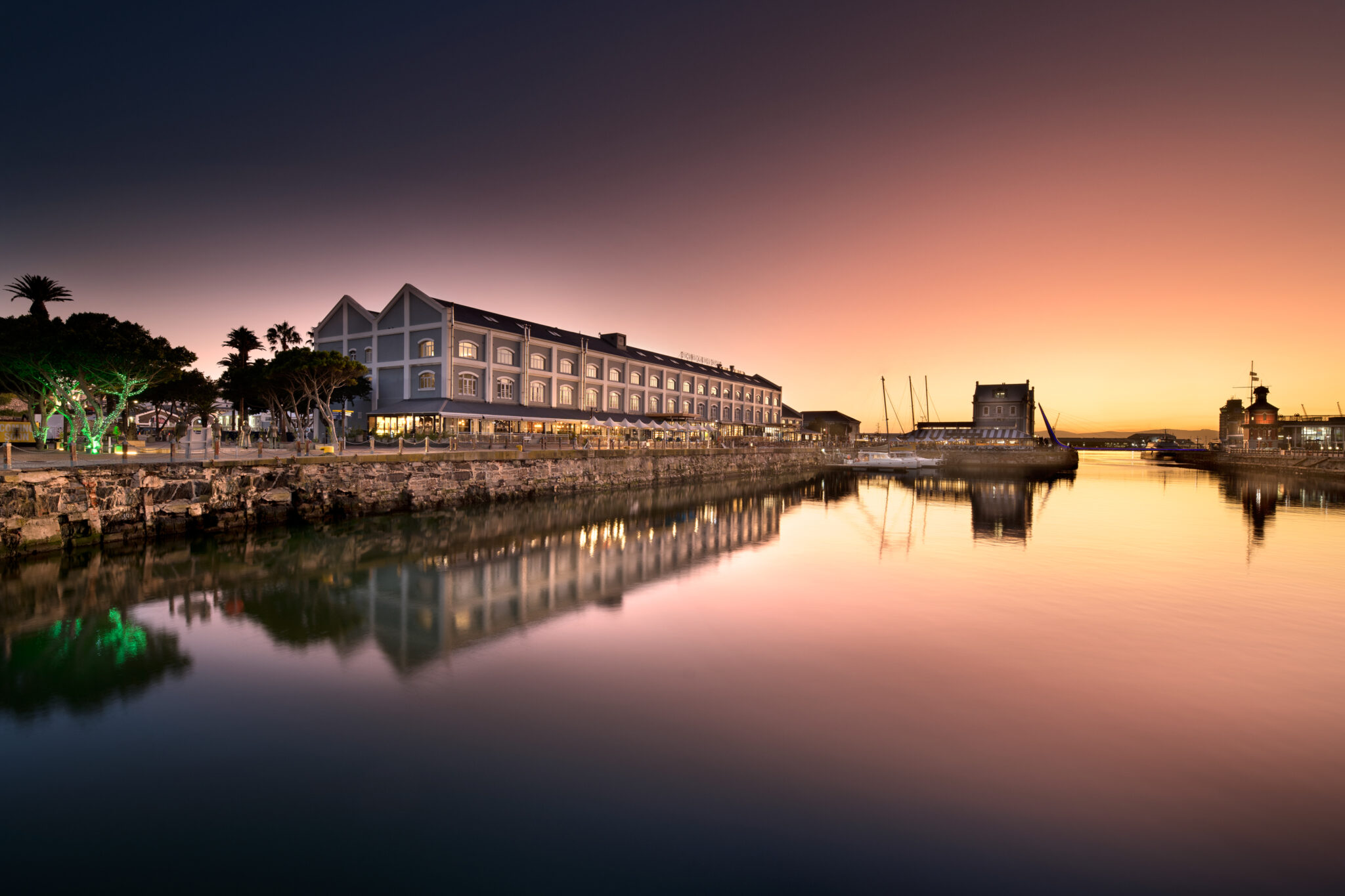 Exterior of Victoria & Alfred Hotel at sunset with view of the marina