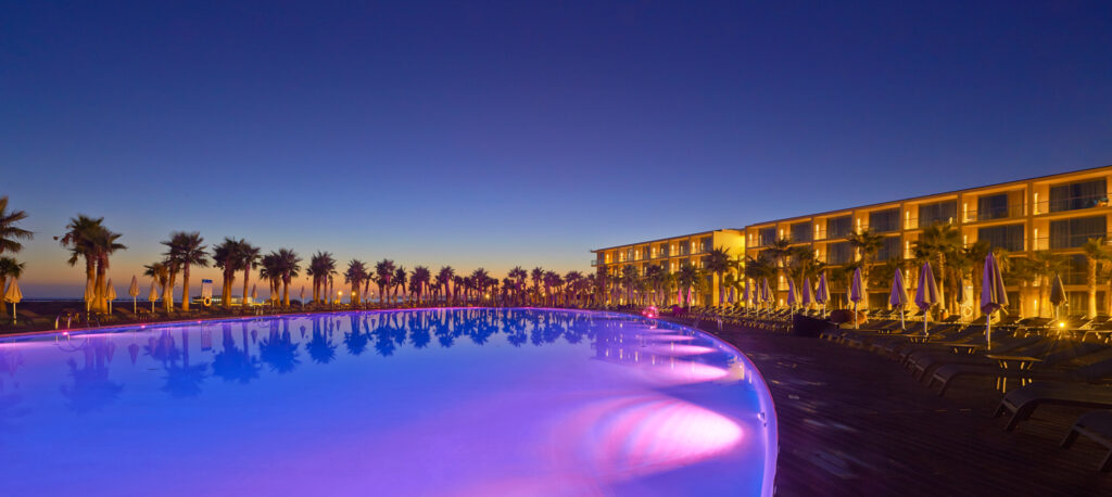 Outdoor pool at night lit up with purple LEDs at Vidamar Resort Hotel Algarve
