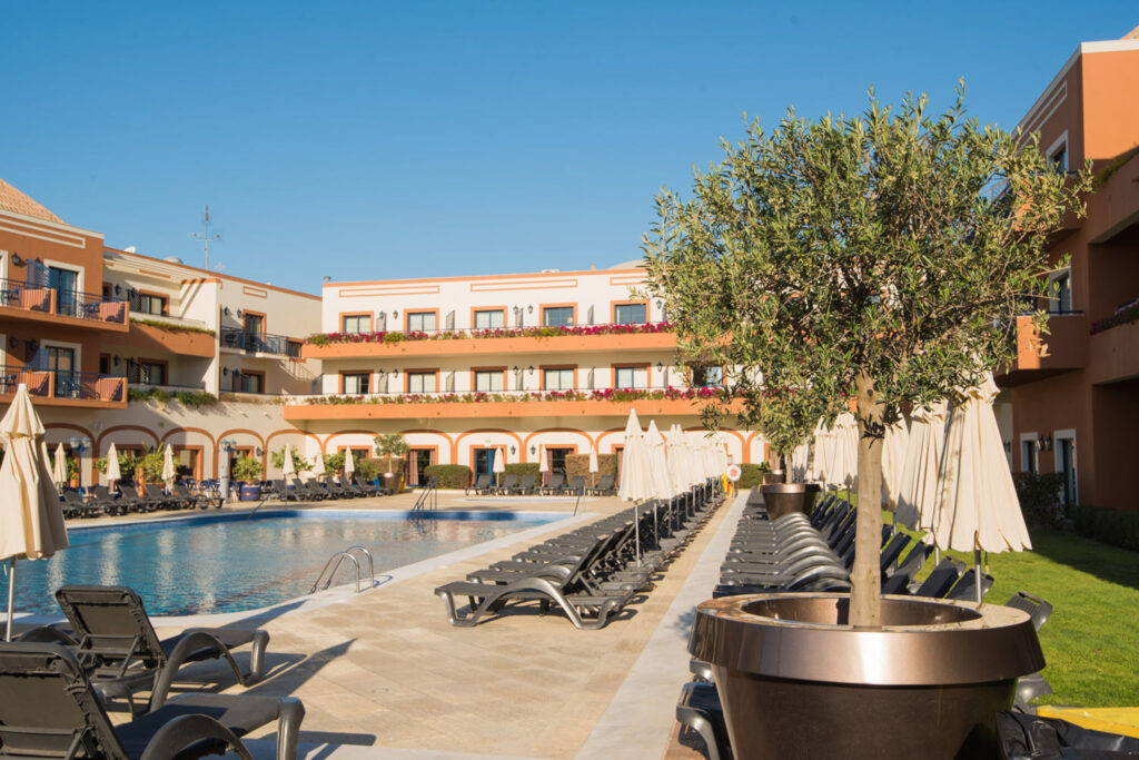 Outdoor pool with sun loungers and accommodation in the background at Vila Gale Tavira