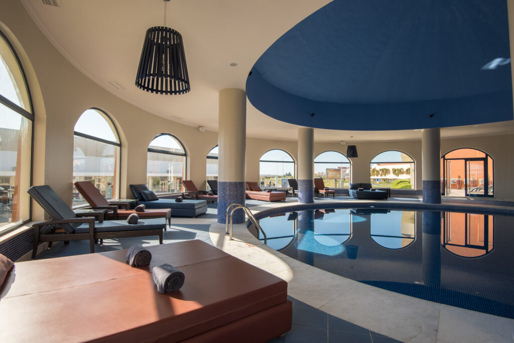 Indoor pool with loungers around it at Vila Gale Tavira