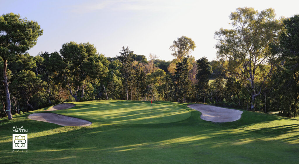 A hole with a red flag with bunkers at Villamartin Golf Course