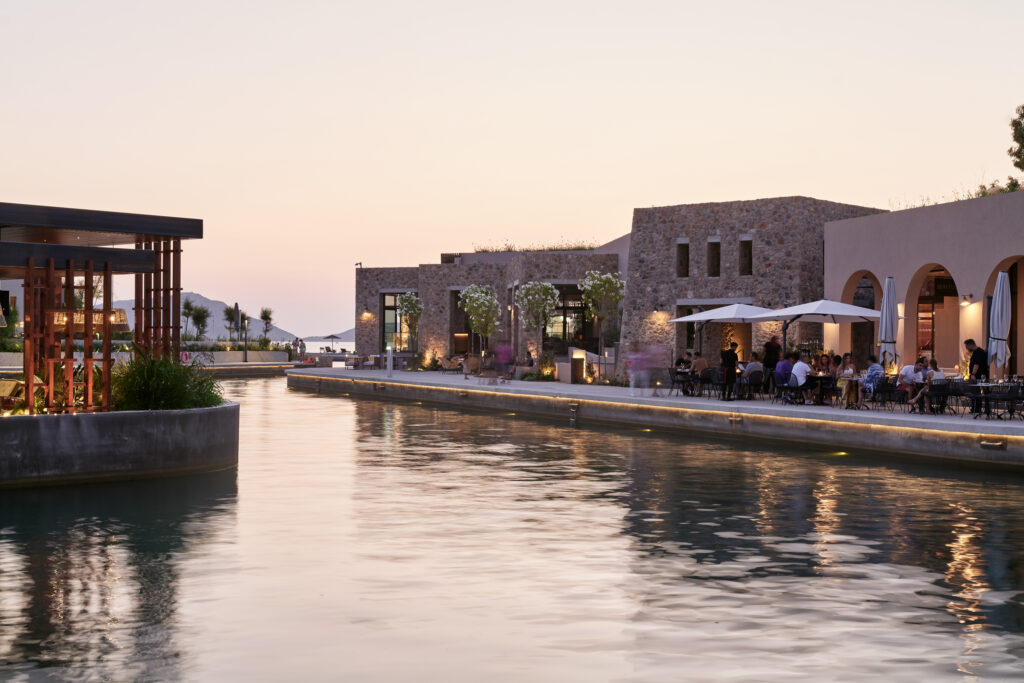 Outdoor pool at W Costa Navarino with people dining in background