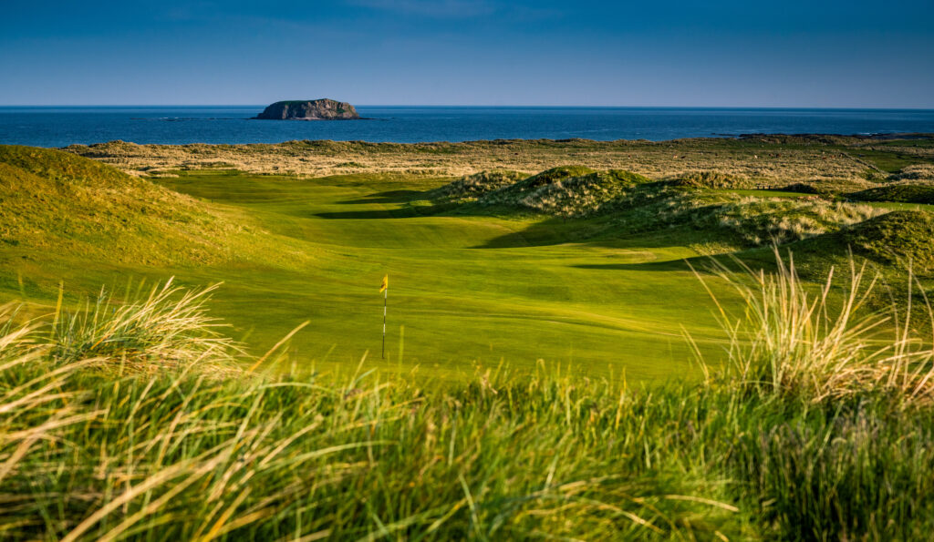 Hole with yellow flag at Ballyliffin Golf Club - Old Links with ocean in background