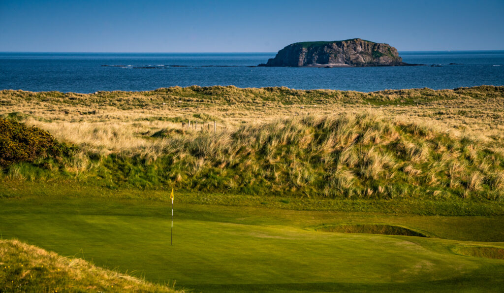 Hole with yellow flag at Ballyliffin Golf Club - Old Links with ocean in background