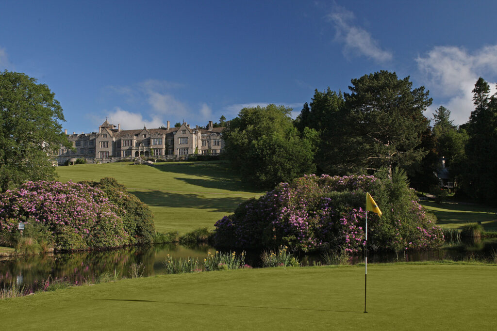 Hole with yellow flag at Bovey Castle with hotel in background