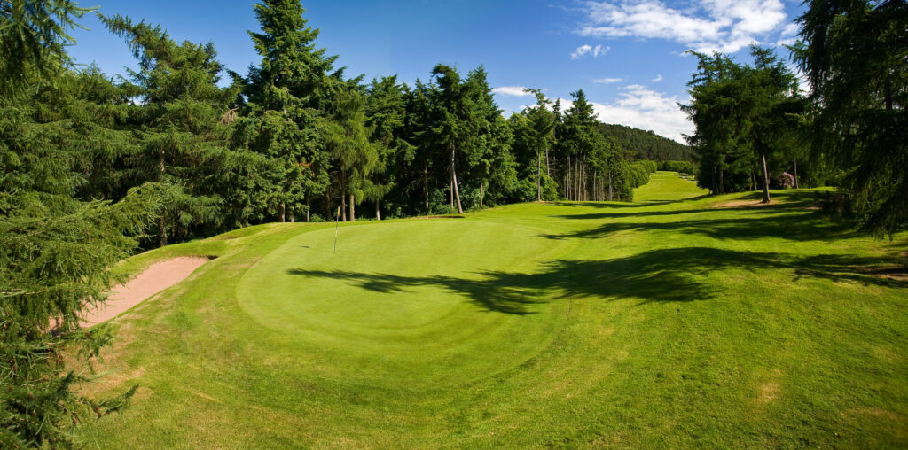 Hole with yellow flag and trees around at Carden Park - Cheshire Course