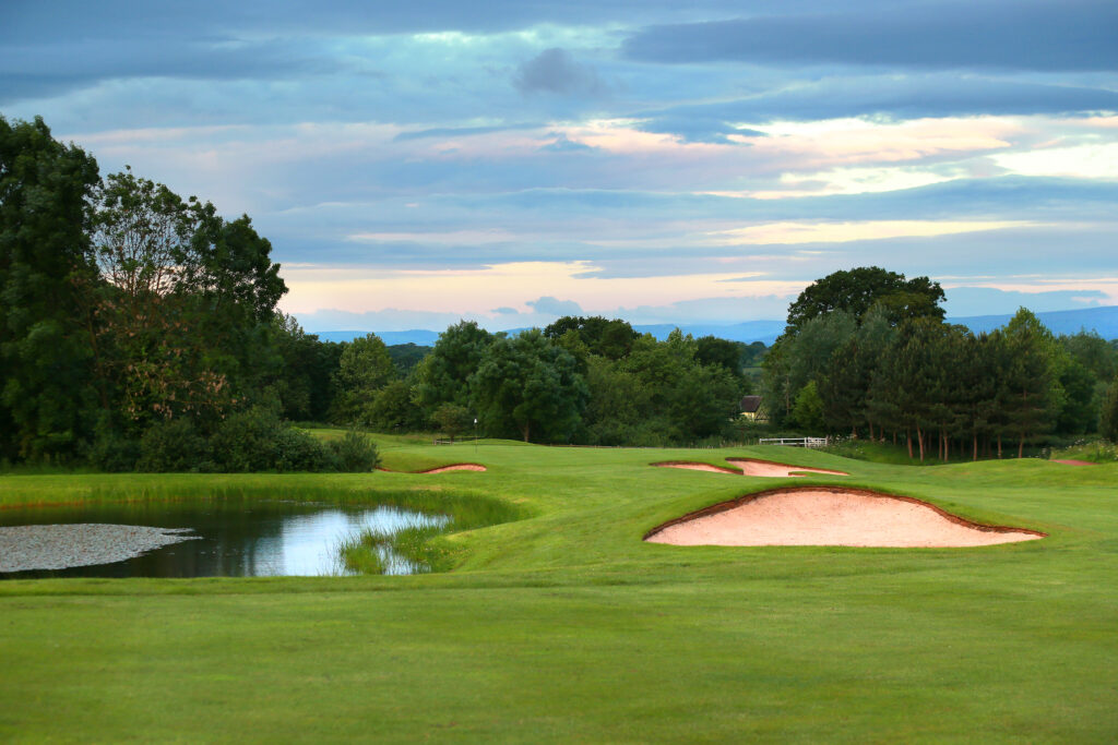 Bunkers on fairway with water hazard and trees around at Carden Park - Nicklaus Course