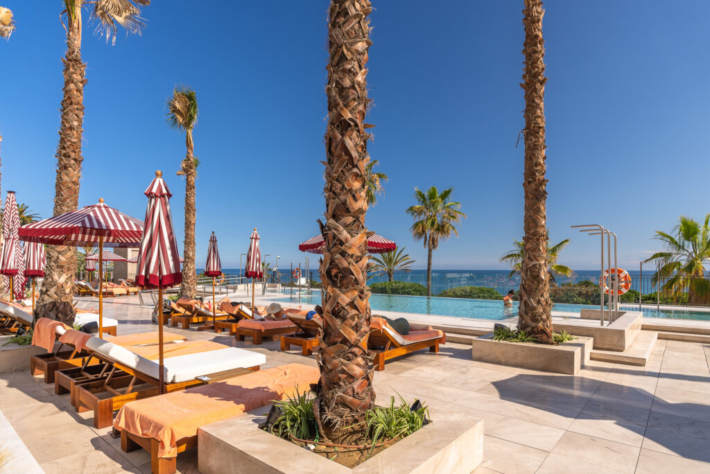 Sun loungers by outdoor pool at El Fuerte Marbella