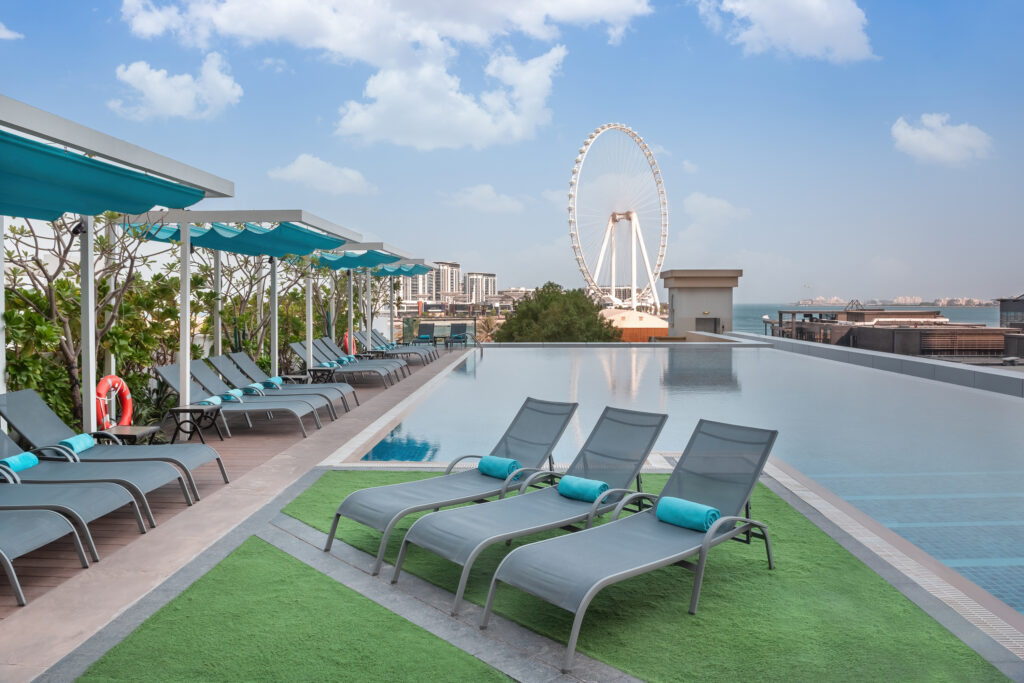 Outdoor pool with sun loungers at JA Ocean View Hotel