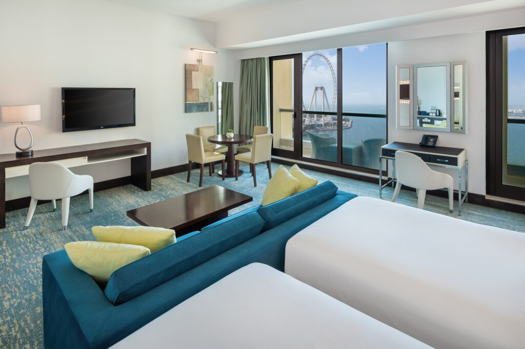 Twin bed accommodation with seating area at JA Ocean View Hotel