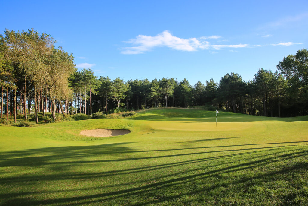 Hole with bunker at Belle Dune with trees around