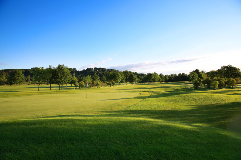 Hole with white flag at Belton Woods - Lakes Course with trees around