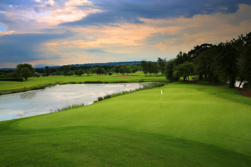 Hole with white flag with lake next to it and trees around at Belton Woods - Lakes Course