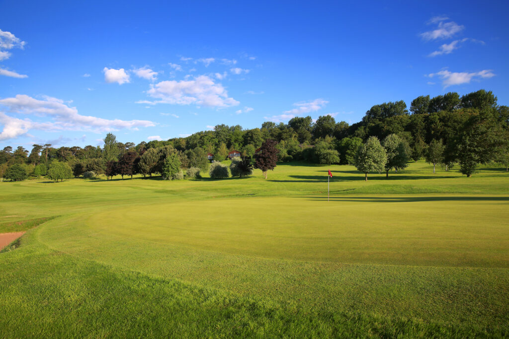 Hole with red flag at Belton Woods - Woodside Course with trees around