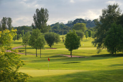 Hole with red flag at Belton Woods - Woodside Course with trees around