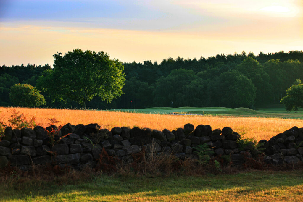 Stone wall with fairway and trees in background at Breadsall Priory - Moorland Course