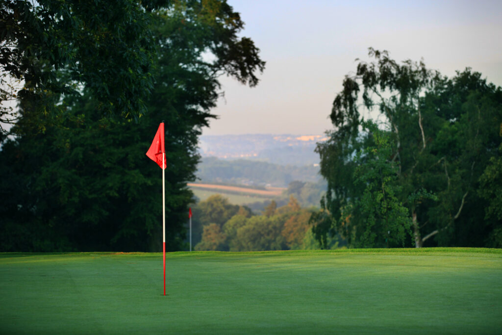 Hole with red flag at Breadsall Priory - Moorland Course with trees around