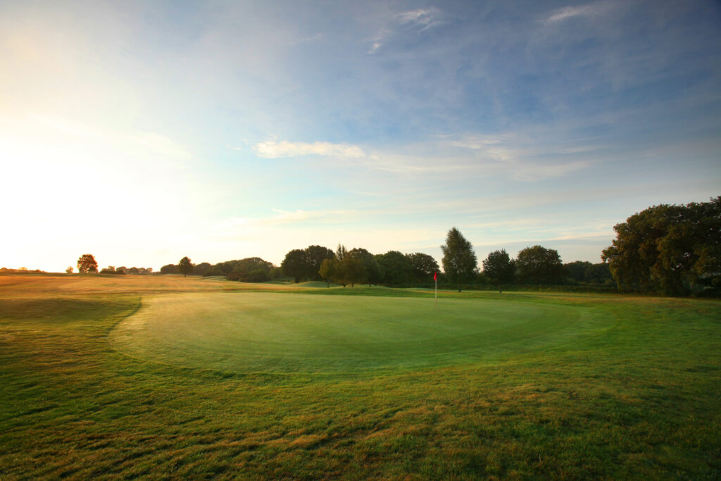 Hole with red flag with trees around at Breadsall Priory - Moorland Course