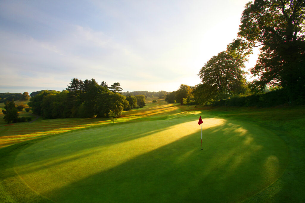 Hole with red flag at Breadsall Priory - Moorland Course with trees around