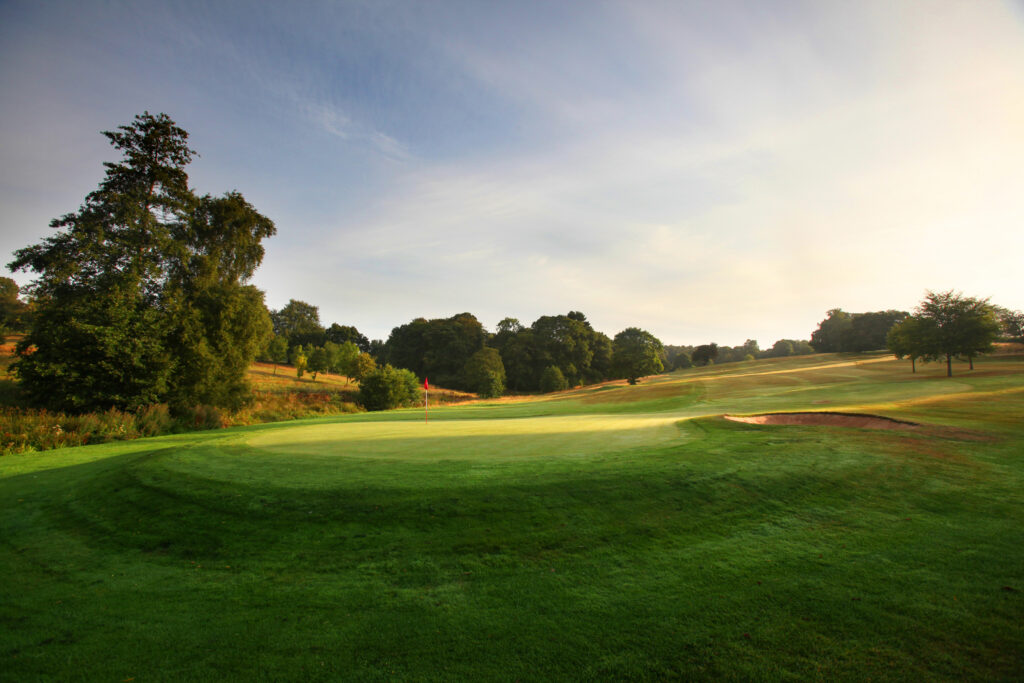 Hole with red flag at Breadsall Priory - Moorland Course with trees around