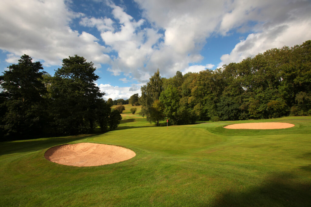 Hole with red flag and bunkers with trees around at Breadsall Priory - Moorland Course