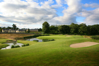 Bunker on fairway with trees and buildings in background at Druids Heath Course