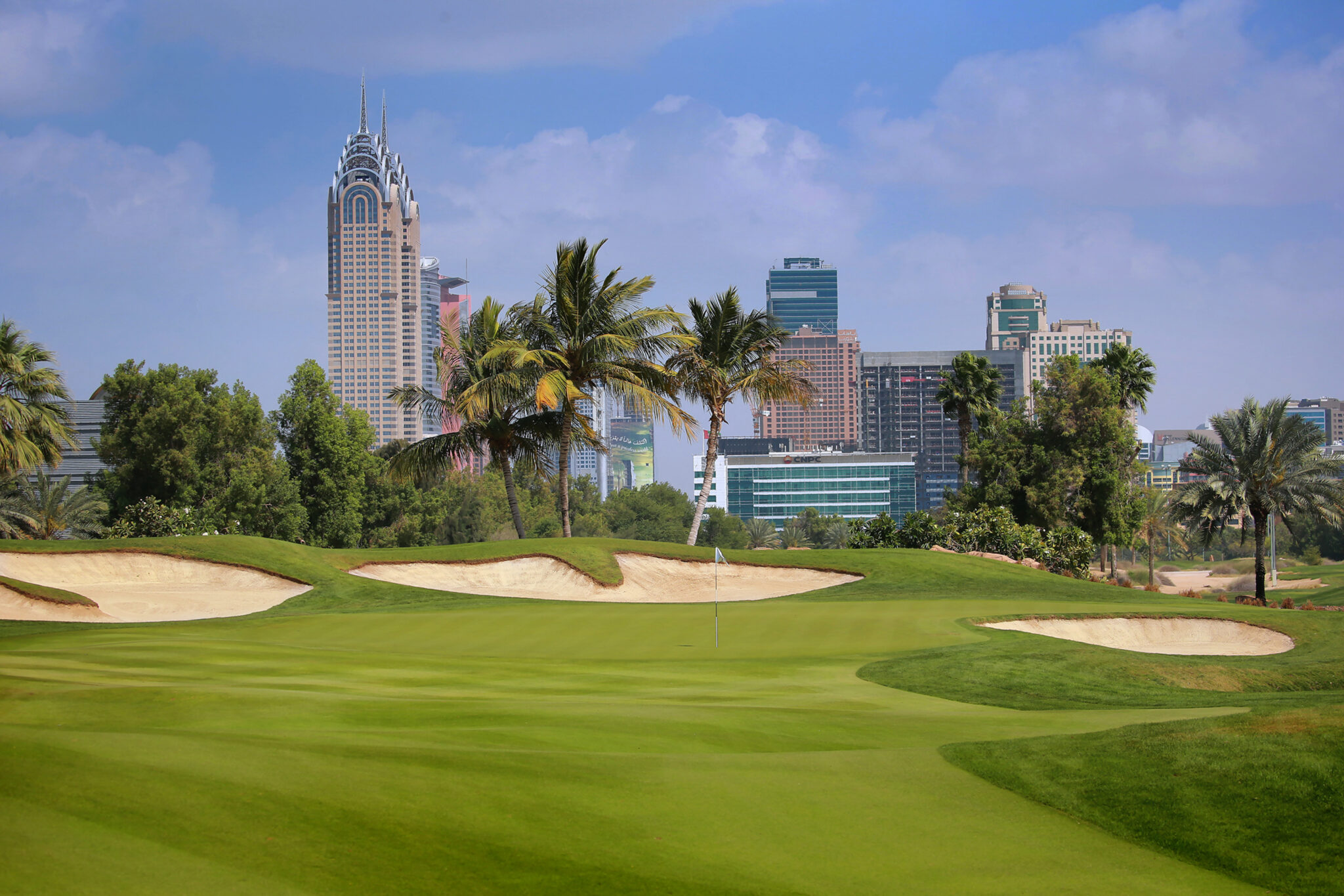 Hole with bunkers around at Emirates Golf Club - The Faldo with buildings in distance