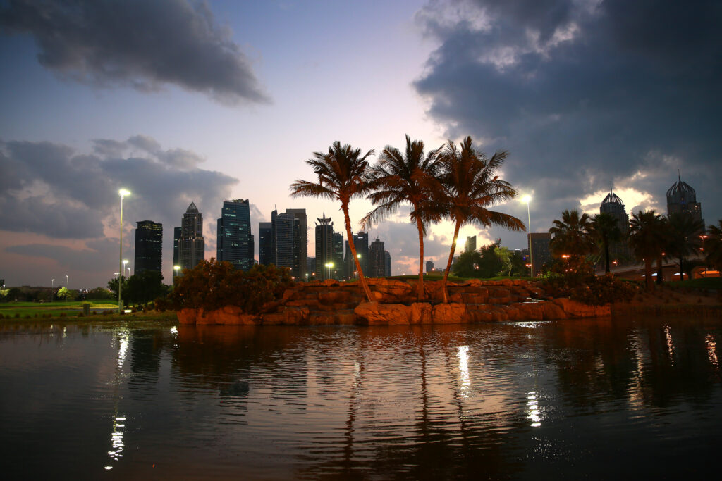 Lake on fairway with buildings in distance at Emirates Golf Club - The Faldo at night