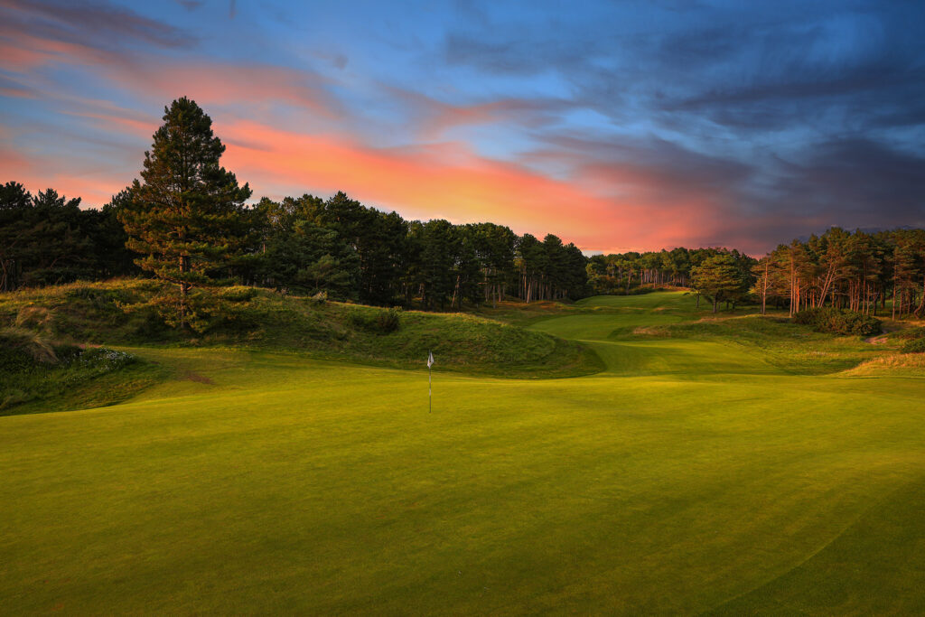 Hole with white flag with trees around at Formby Golf Club