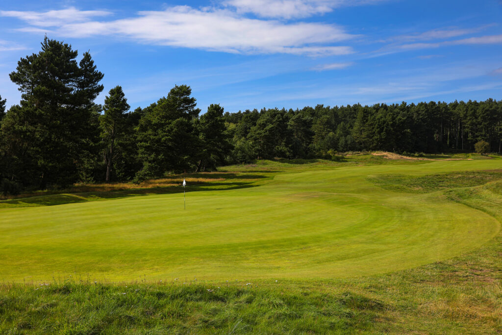 Hole with white flag with trees around at Formby Golf Club