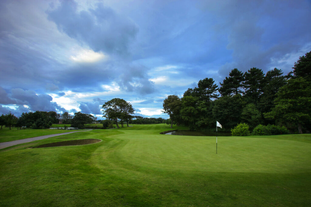 Hole with white flag with trees around at Formby Hall - Championship Old Course