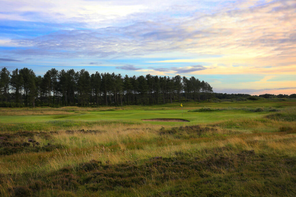 Hole with yellow flag with trees in background at Formby Ladies Golf Club