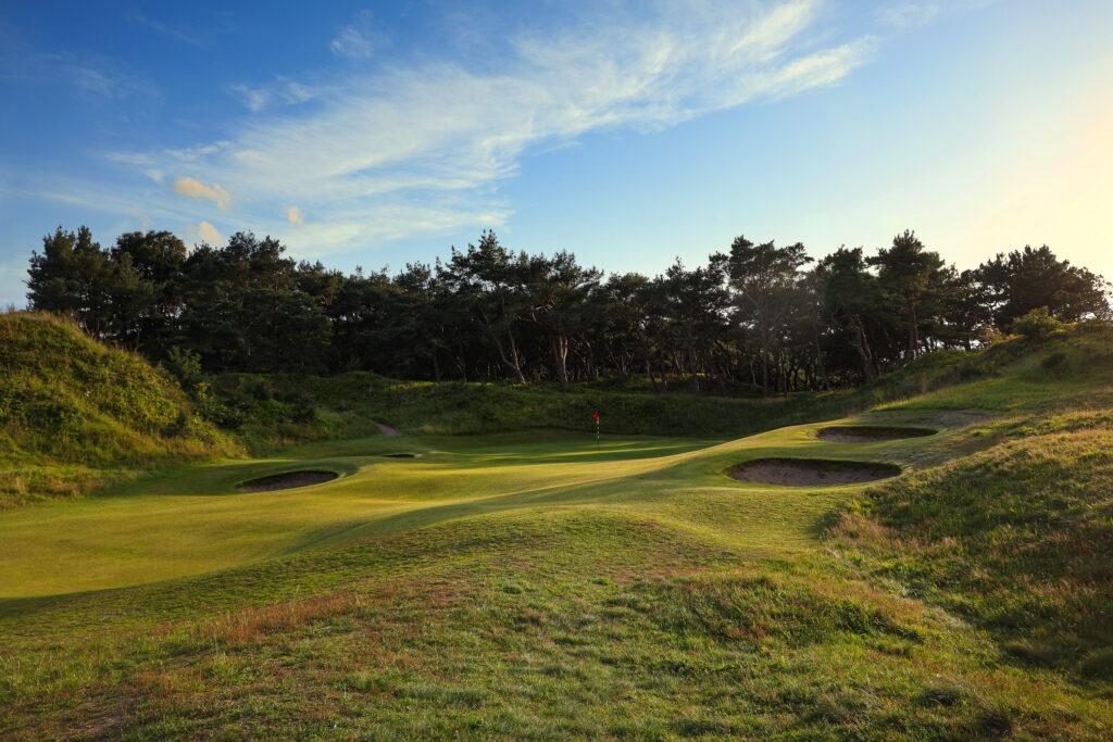 Hole with bunkers around at Formby Ladies Golf Club with trees around