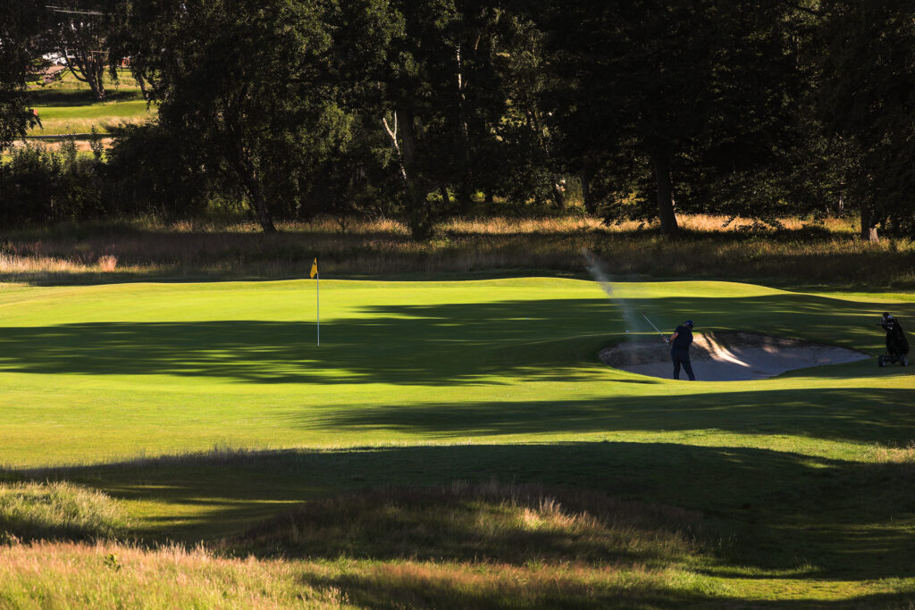 People playing golf out of a bunker at Hillside Golf Club