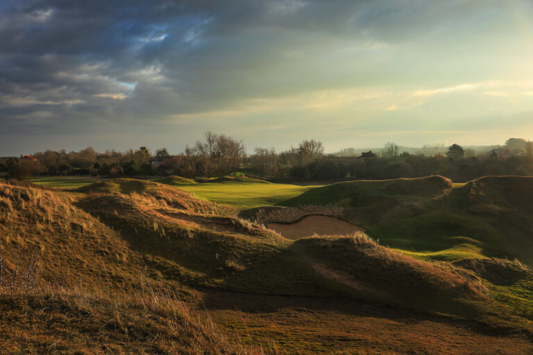 Bunkers and mounds around hole with red flag at Hunstanton Golf Club