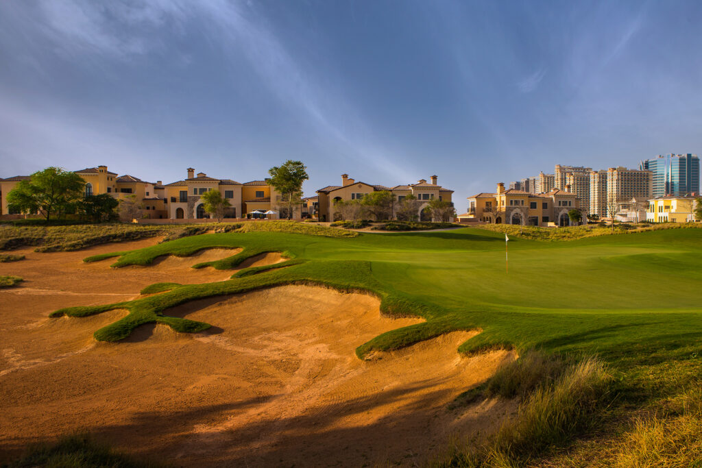 Hole with bunkers at Jumeirah Golf Estates - Fire Course with buildings in background