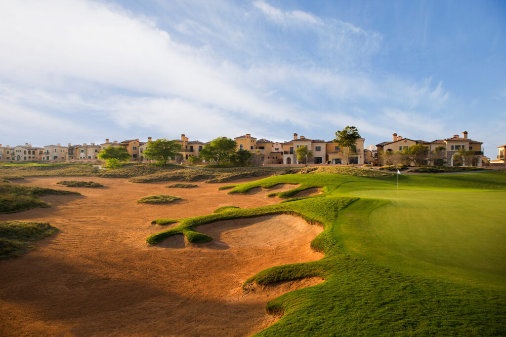 Hole with bunkers at Jumeirah Golf Estates - Fire Course with buildings in background