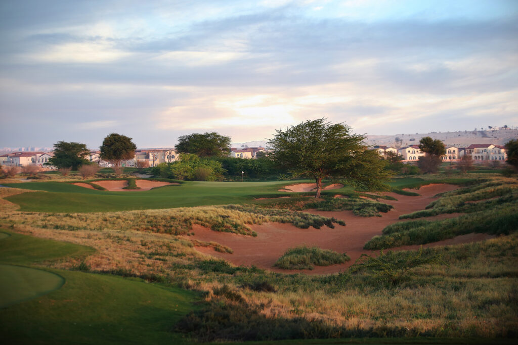 Bunkers on fairway at Jumeirah Golf Estates - Fire Course with trees and buildings in background