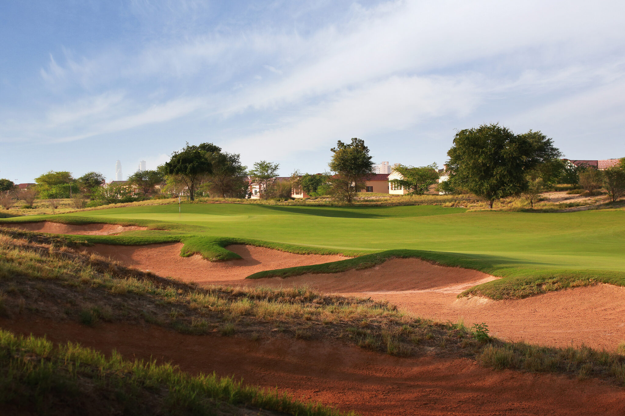 Bunkers on fairway at Jumeirah Golf Estates - Fire Course with trees and buildings in background