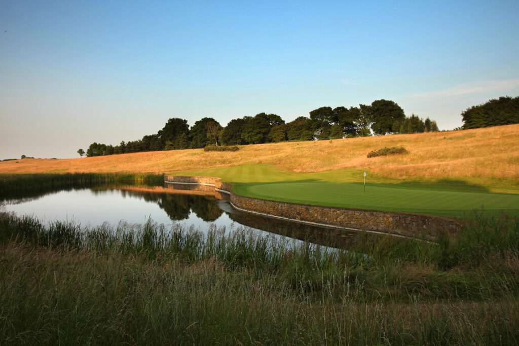 Hole with water hazard at The London Golf Club with trees in distance