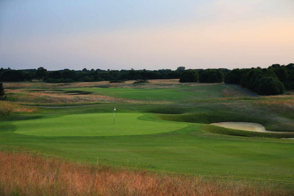 Hole with bunker at The London Golf Club with trees in background