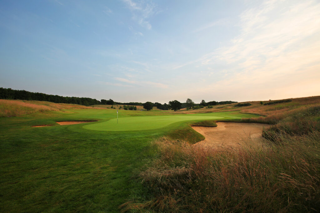 Hole with bunker at The London Golf Club with trees in background