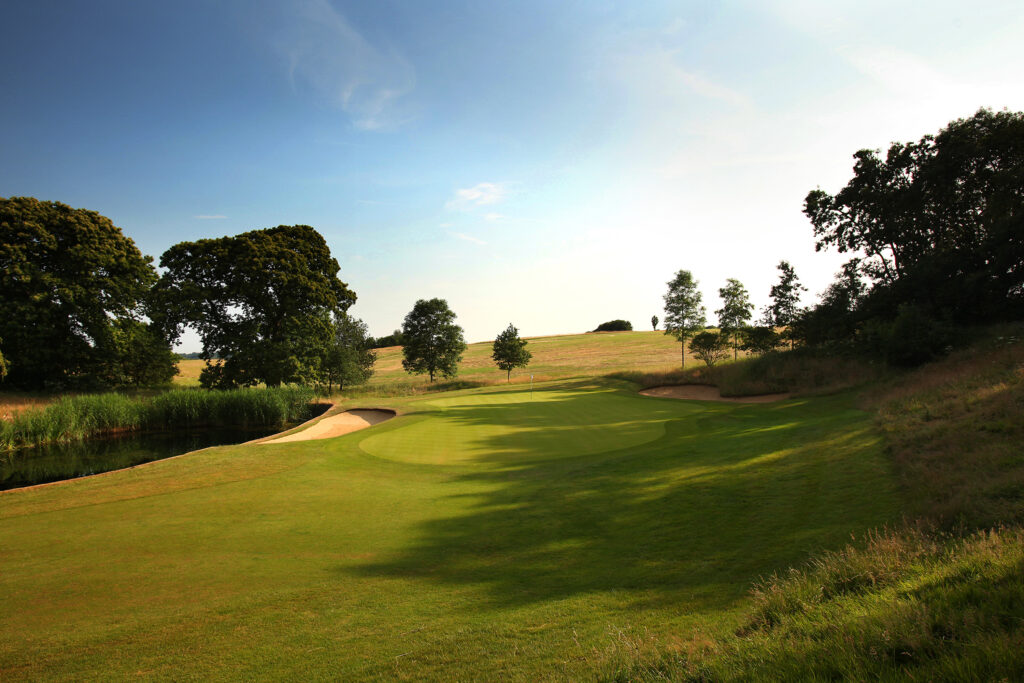 Hole with bunker and water hazard with trees around at The London Golf Club