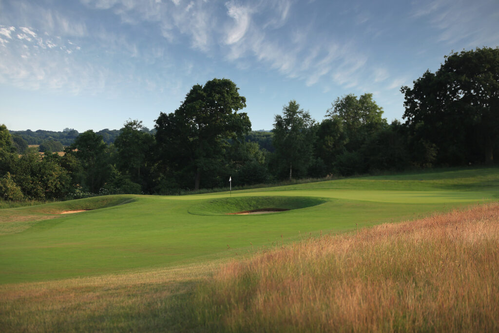 Hole with bunkers around at The London Golf Club with trees in background