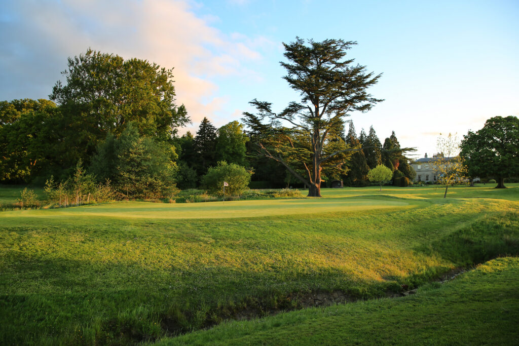 Hole with white flag with trees around at Macdonald Linden Hall Golf Course