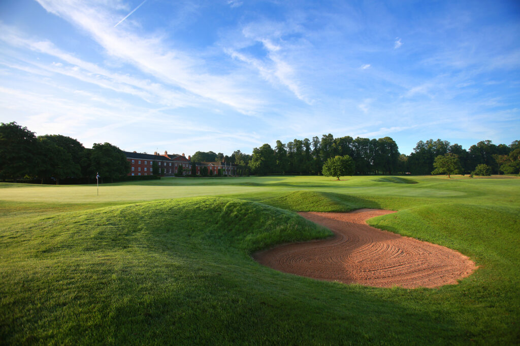 Hole with bunker and building in background at Mottram Hall Golf Course